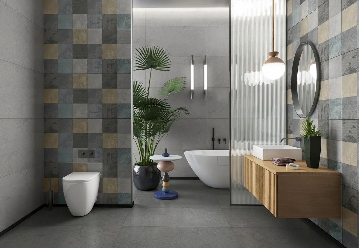 Baño con paredes de piezas grises y decorativas, lavatorio sobre mueble de madera y espejo circular.