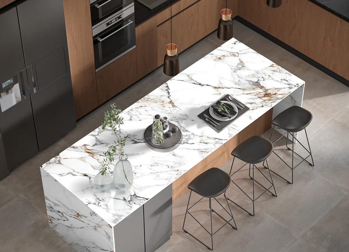 Cocina con isla de superficie blanca veteada, muebles de madera y piso gris.